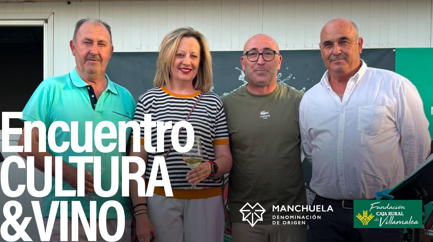 Fotografía de grupo del presidente de la D.O. Manchuela, José Enrique, junto al Delegado de Agricultura de Albacete, Ramón, y asistentes al Encuentro Cultura y Vino en Villamalea. De fondo, cartel del evento con el logotipo de la denominación y el de la Fundación Caja Rural de Villamalea.