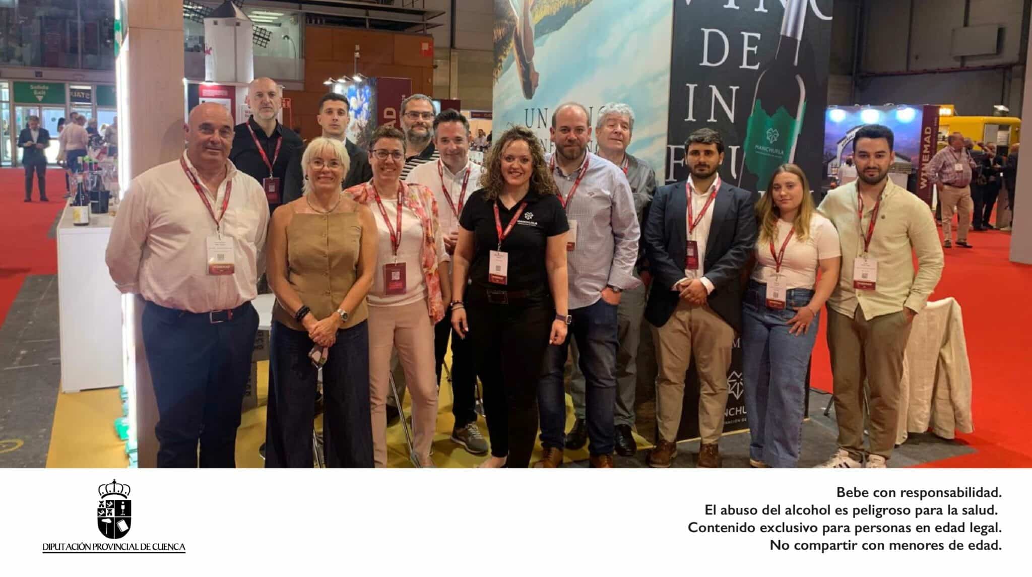 Imagen de grupo del equipo de la Denominación de Origen Manchuela y representantes de las bodegas participantes posando en el Stand 620 de la feria internacional WineMad 2026 en IFEMA Madrid, con el lema 'Vino de Influencia' y el logo de la Diputación Provincial de Cuenca.
